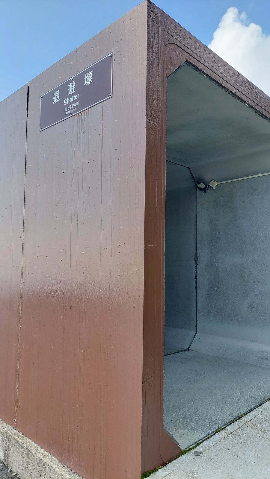 Front view of the volcanic shelter structure showing the protective glass and metal cladding