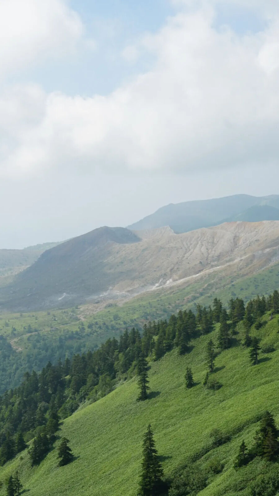 Barren volcanic terrain of Mount Kusatsu-Shirane with sparse vegetation on the lower slopes and grey rock above
