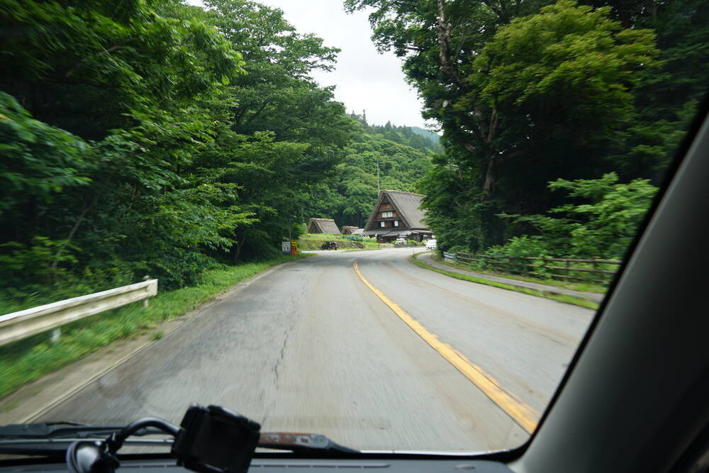 Arriving at Shirakawa-go by campervan, a Gassho house visible at the end of a mountain road