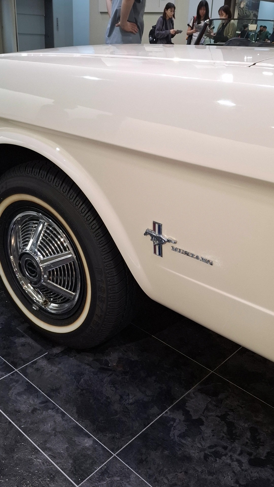 Mustang fender badge detail with running horse and chrome wire wheel with whitewall tire