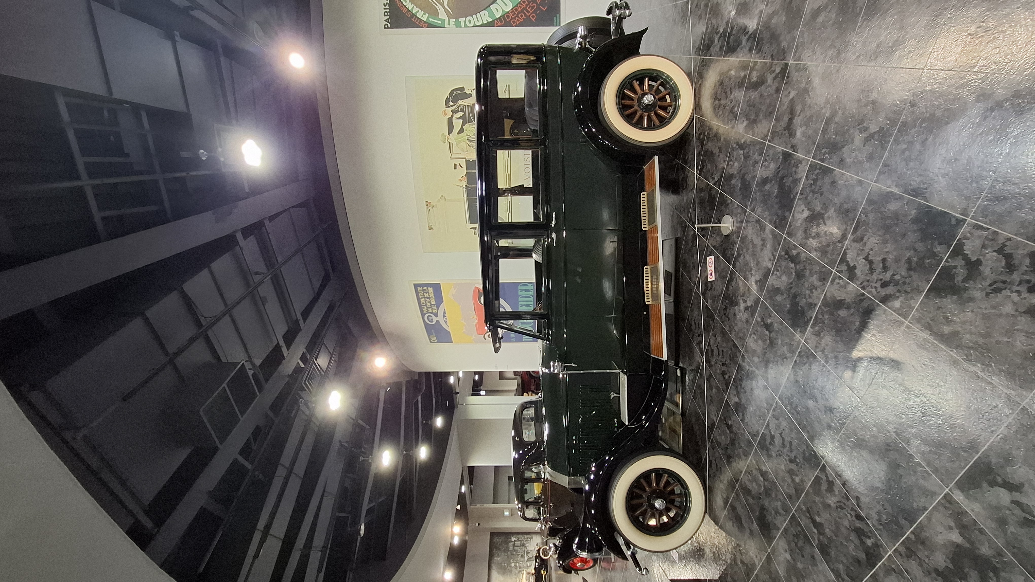 Green 1920s touring car with wood-spoke wheels and folding canvas top