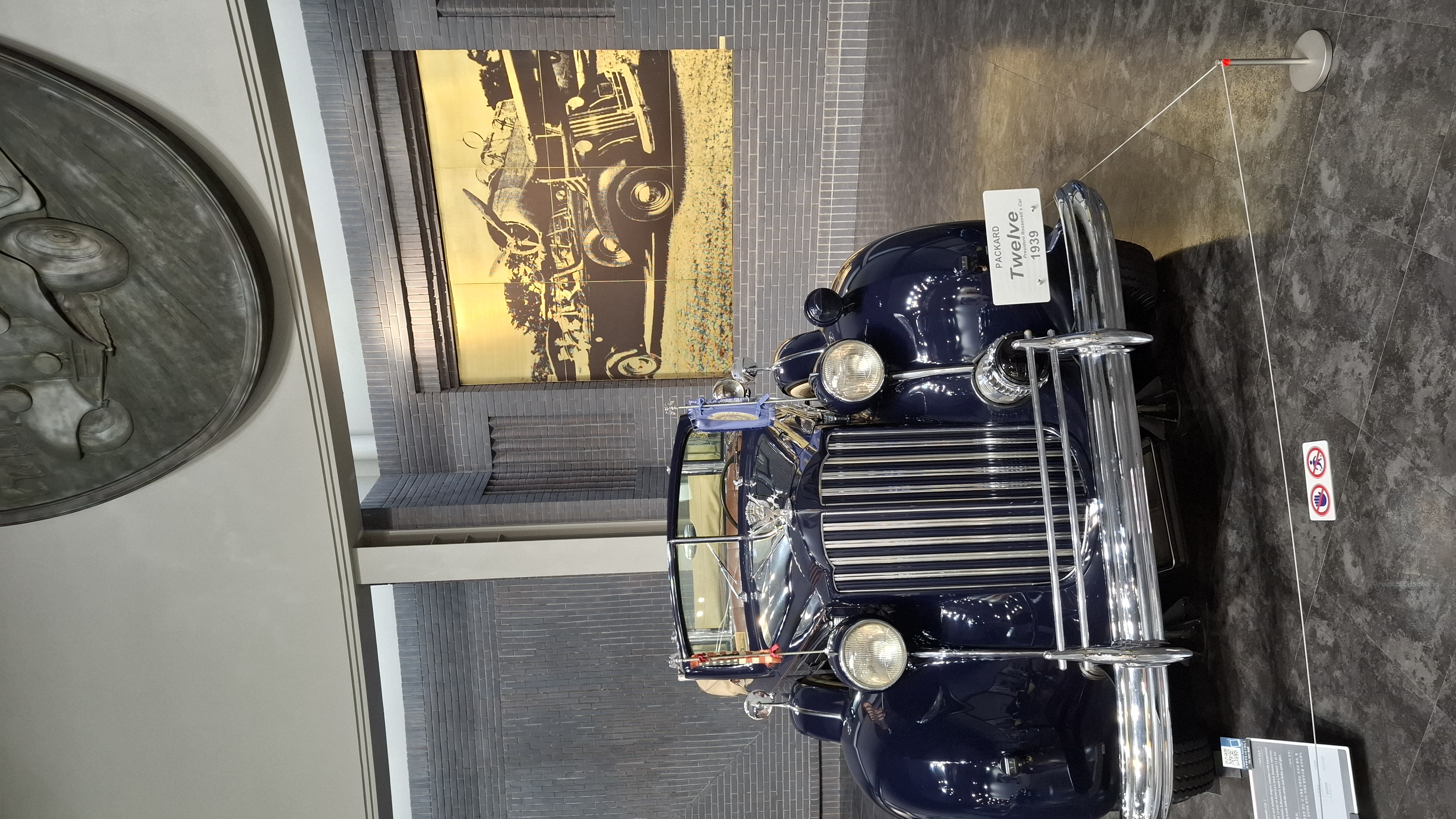 Presidential Packard limousine front view, chrome grille and dark blue paint, period photographs behind