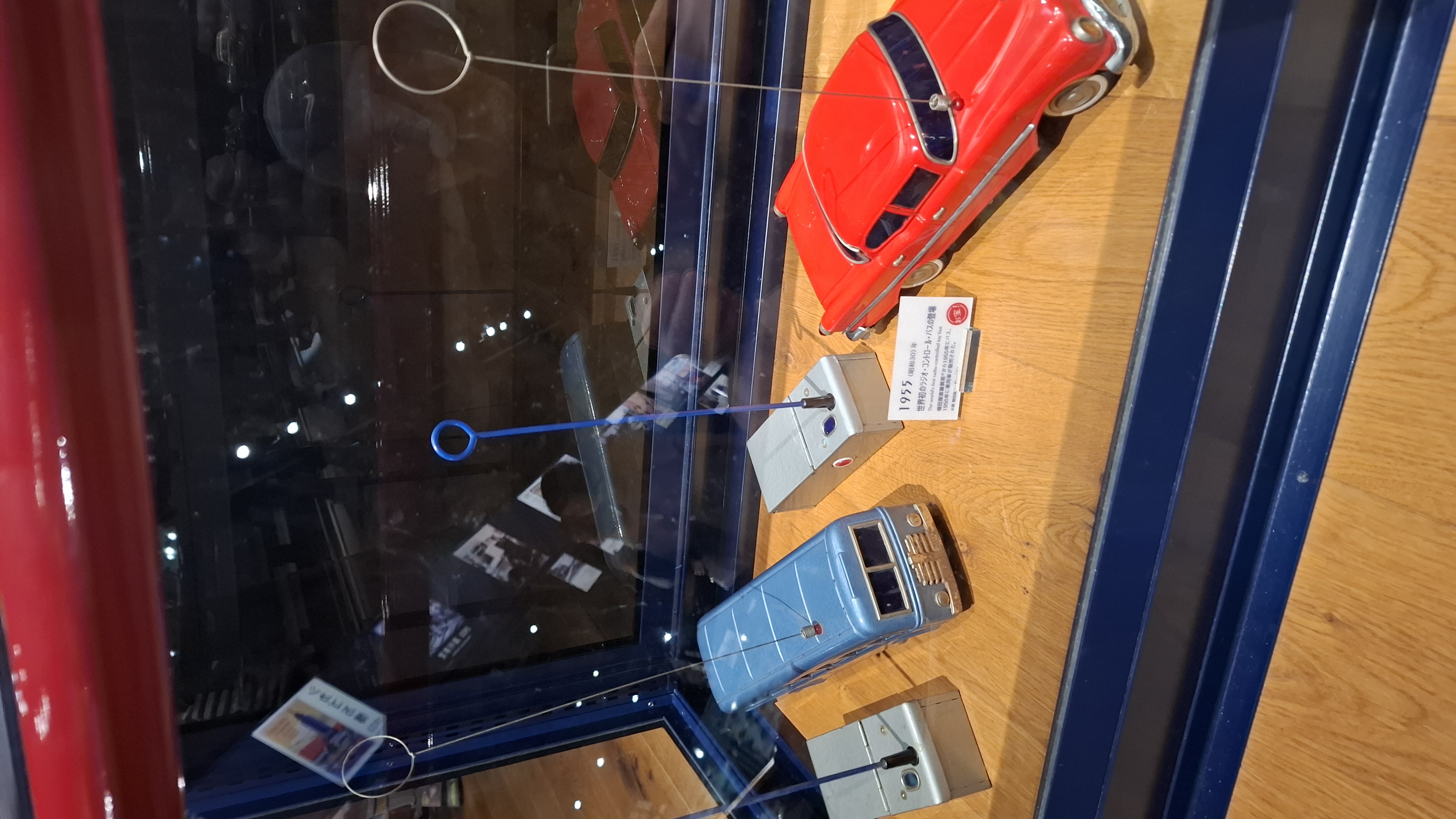 Scale model car display detail, a red sports car and blue sedan in a glass case