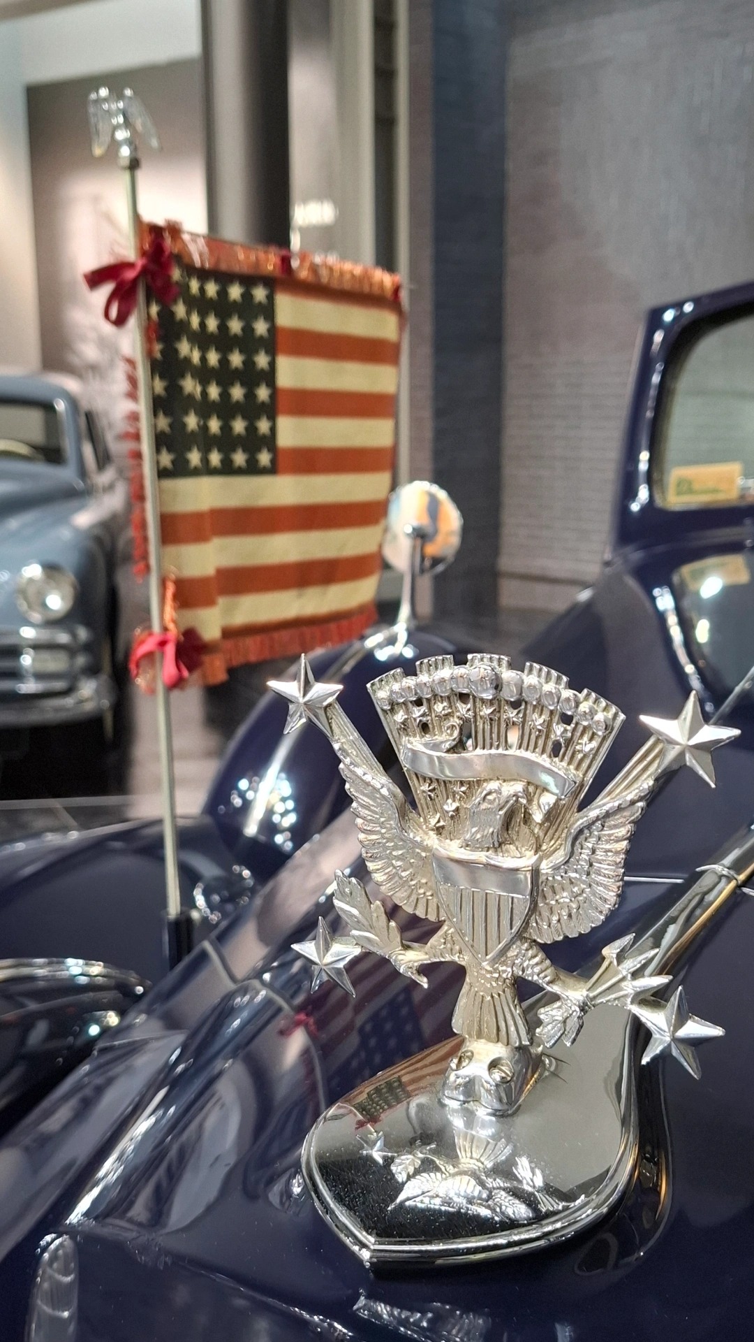 US Presidential limousine: silver eagle with spread wings and stars on the hood, American flag with gold fringe behind