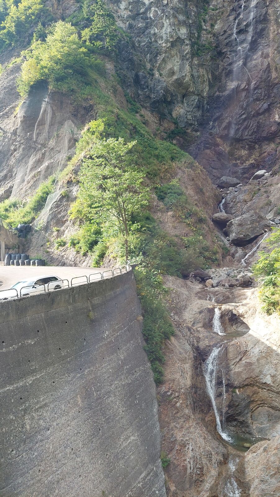 Looking straight down the face of the dam wall into the gorge below, the river visible at the bottom