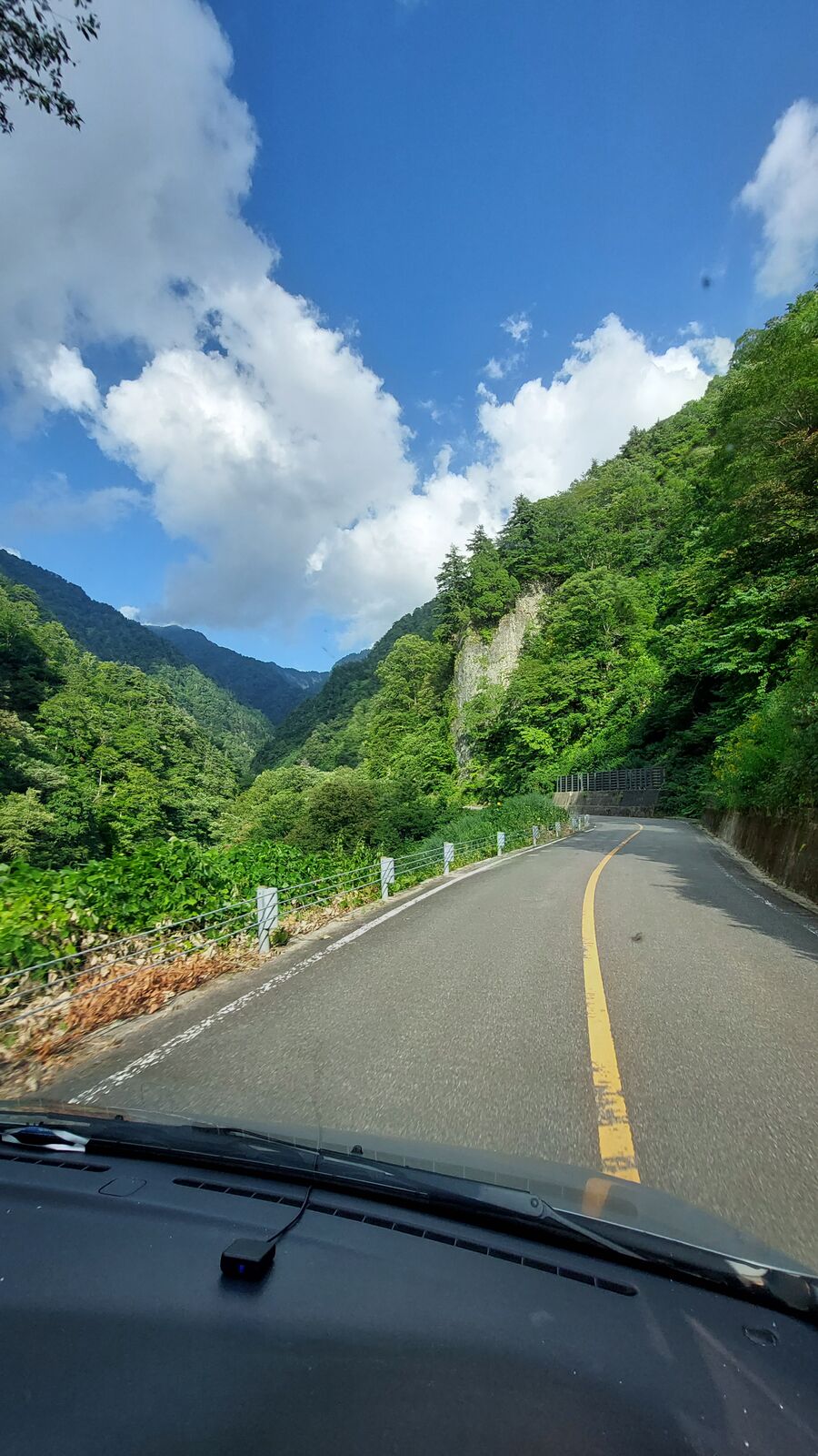 Driving through the mountain pass, road stretching ahead between green slopes and deep valley