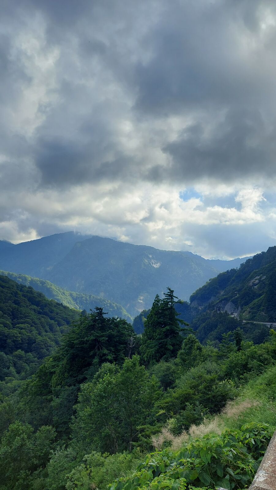 Moody view into a deep mountain valley with clouds building over the peaks