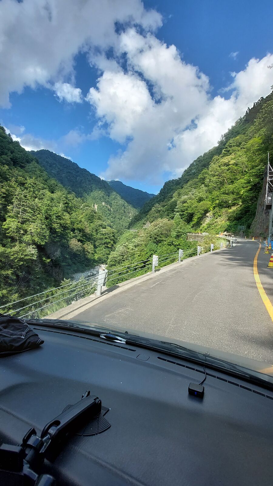 The road ahead with tunnel entrance visible, green mountains rising steeply on both sides