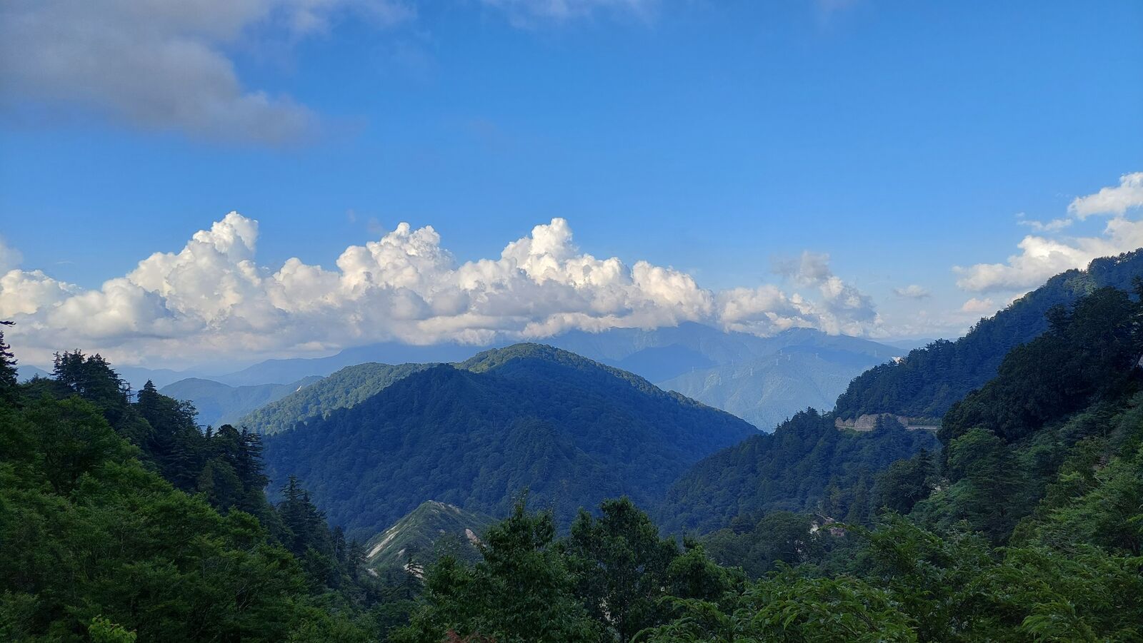 View from near the summit with summer clouds building above the mountain ridges