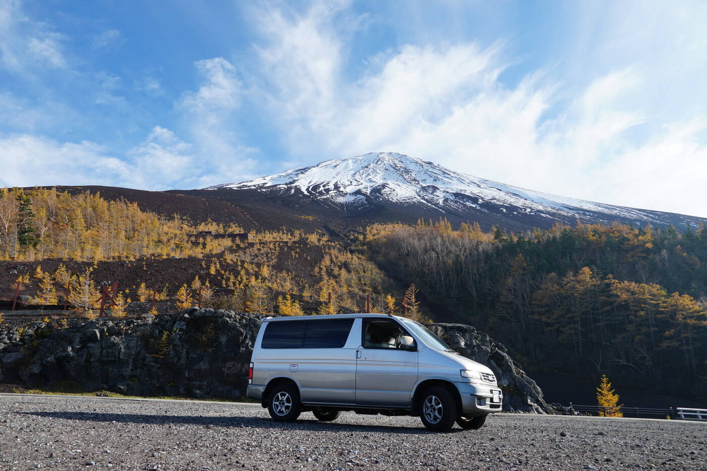 Campervan at Mount Fuji 5th station with snow cap and autumn larches