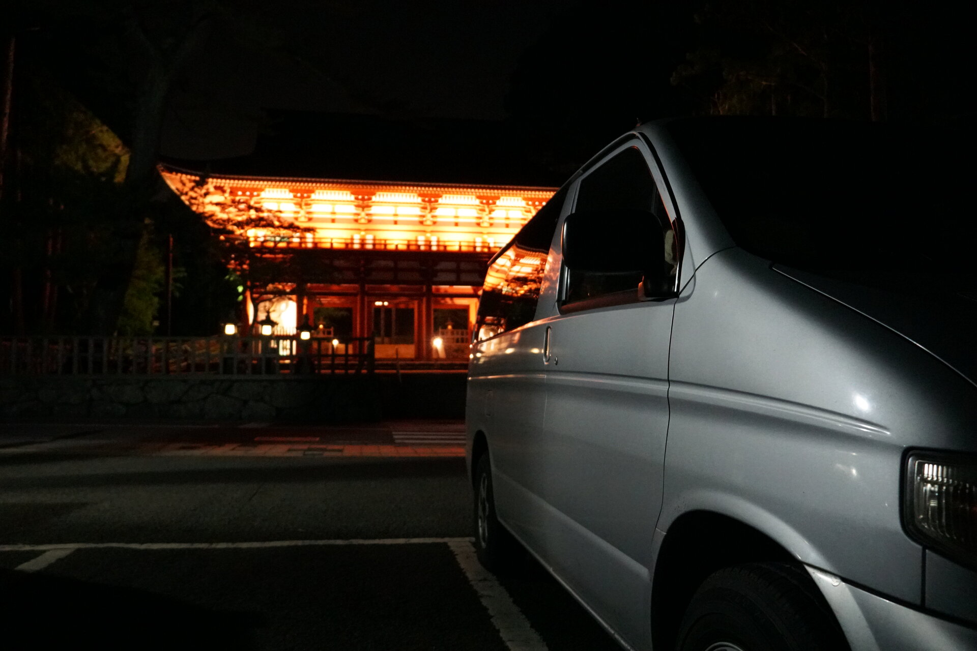 Illuminated Japanese temple gate at night with campervan